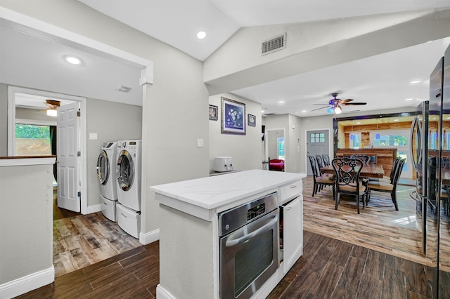 kitchen featuring independent washer and dryer, lofted ceiling, dark hardwood / wood-style floors, stainless steel oven, and ceiling fan