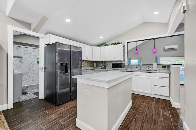 kitchen featuring a kitchen island, stainless steel appliances, vaulted ceiling, and white cabinets