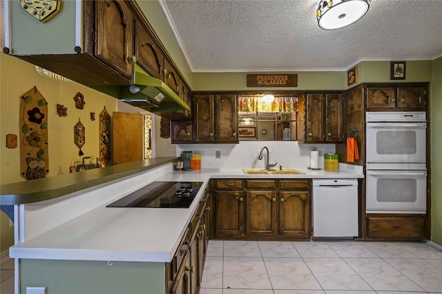 kitchen with kitchen peninsula, dark brown cabinetry, sink, and white appliances