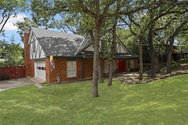 tudor house featuring fence, concrete driveway, roof with shingles, a front lawn, and a chimney