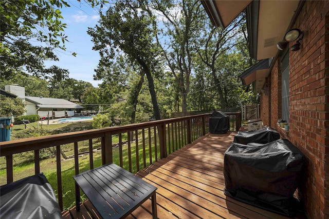 wooden deck with area for grilling, a pool, and a yard