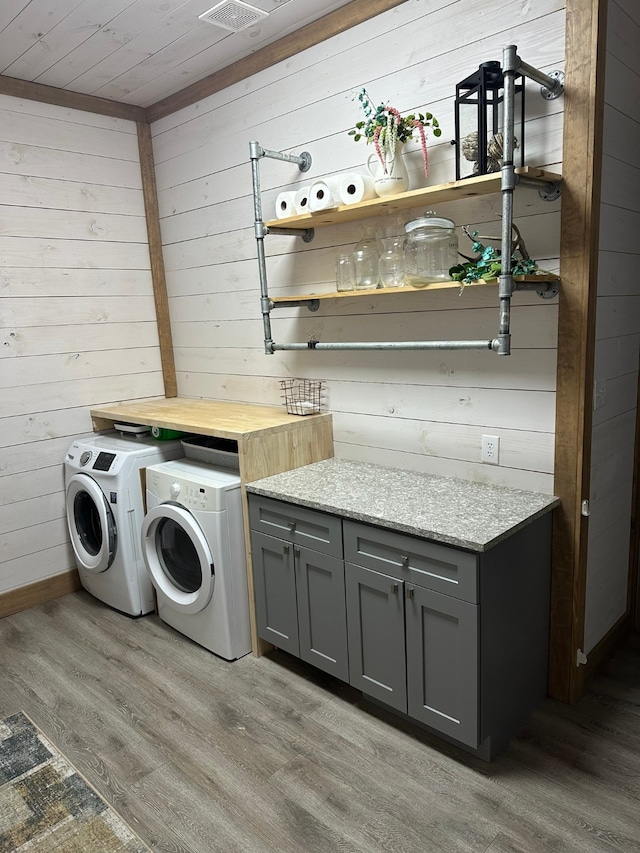 laundry room featuring wooden ceiling, washing machine and dryer, wooden walls, and light hardwood / wood-style floors