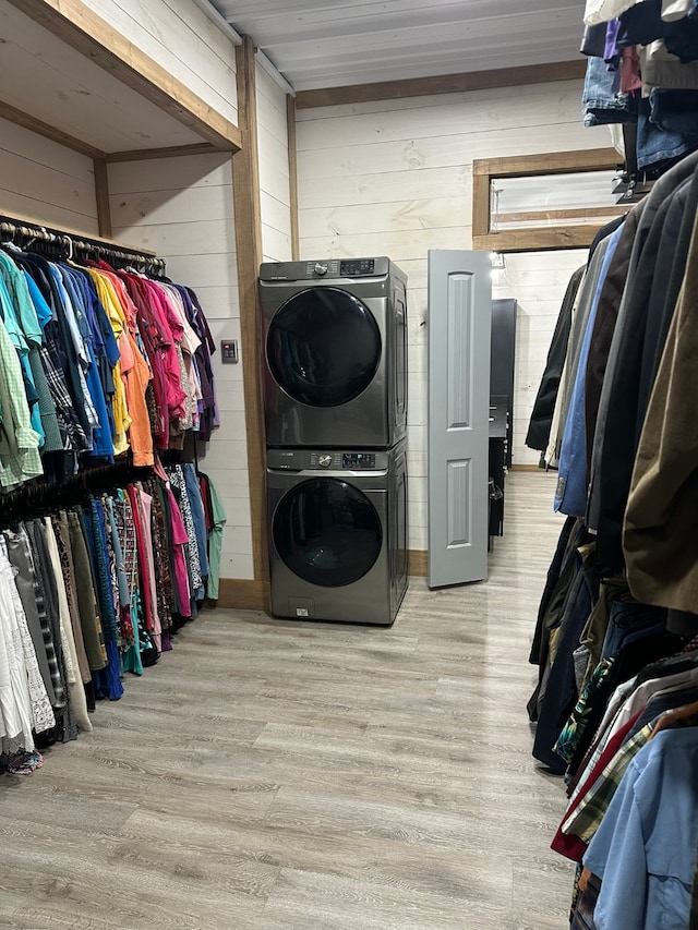 walk in closet featuring stacked washing maching and dryer and light hardwood / wood-style floors