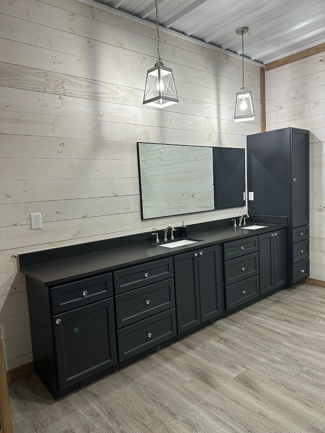 interior space with light wood-type flooring, wood walls, decorative light fixtures, and sink