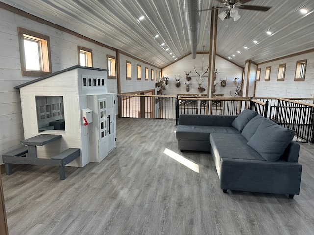 living room featuring ceiling fan, hardwood / wood-style flooring, wooden walls, and vaulted ceiling