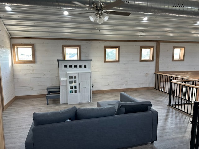 living room featuring ceiling fan, wood walls, and light wood-type flooring