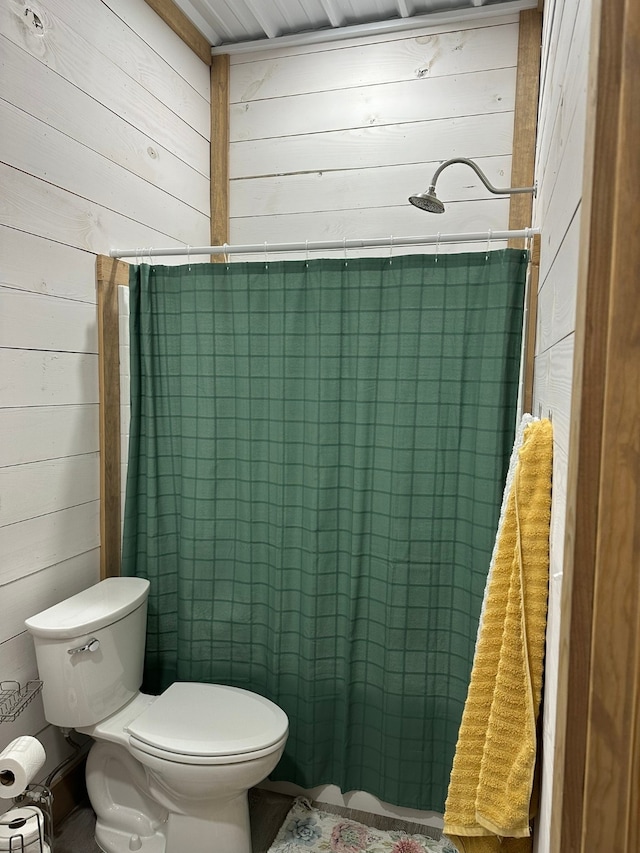 bathroom featuring toilet, walk in shower, and wood walls