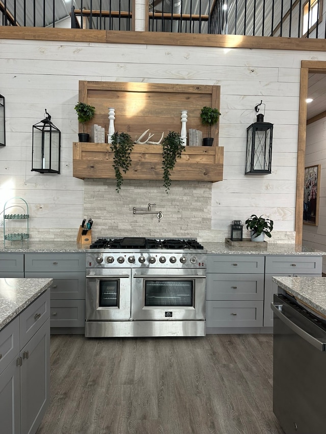 kitchen featuring dark wood-type flooring, light stone counters, stainless steel appliances, and gray cabinetry