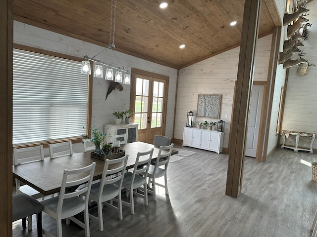 dining area with vaulted ceiling, an inviting chandelier, wood ceiling, hardwood / wood-style flooring, and wooden walls