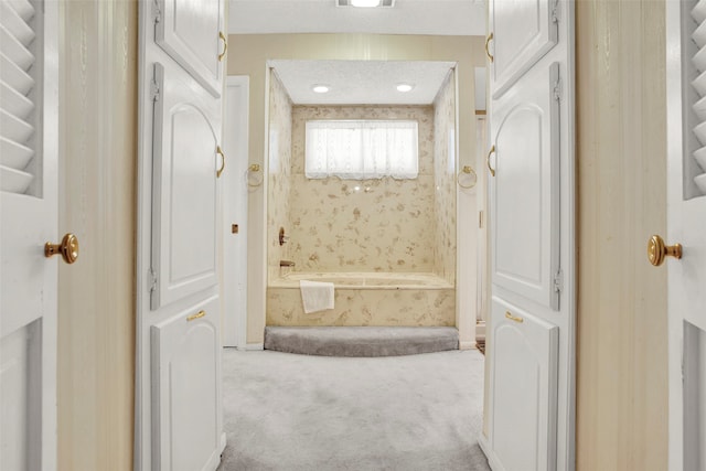 bathroom with a tub to relax in and a textured ceiling