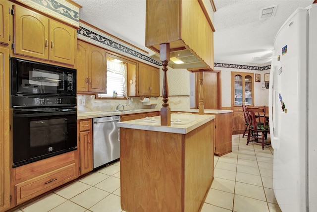 kitchen featuring black appliances, a kitchen island, light tile patterned floors, and a textured ceiling