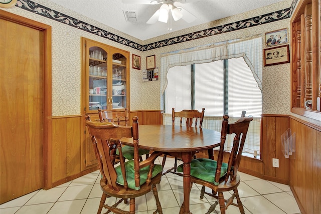 dining space with a textured ceiling, light tile patterned floors, and ceiling fan