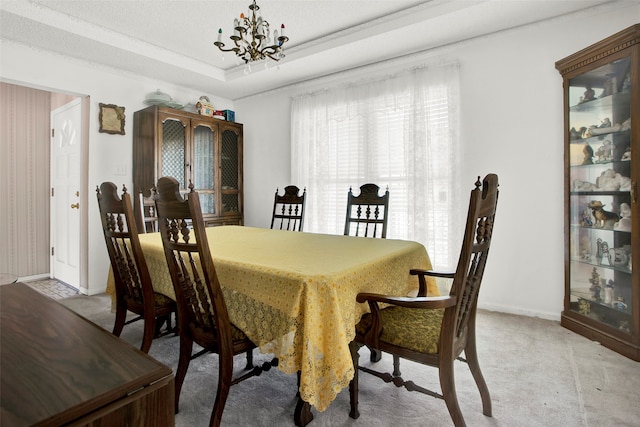 carpeted dining area featuring a tray ceiling, a textured ceiling, and an inviting chandelier