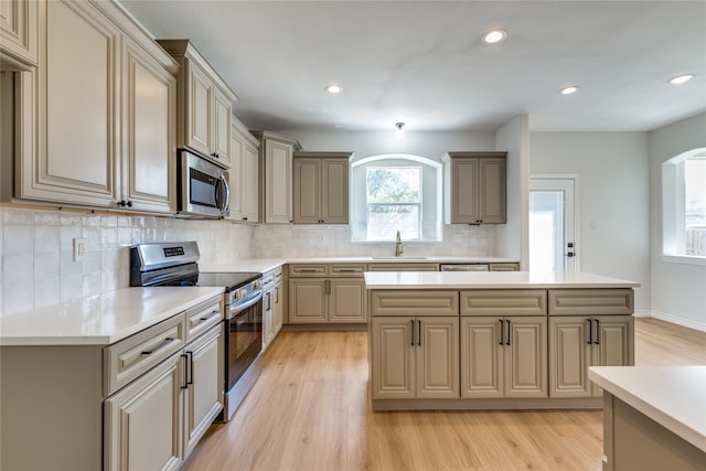 kitchen featuring appliances with stainless steel finishes, decorative backsplash, light hardwood / wood-style floors, and sink