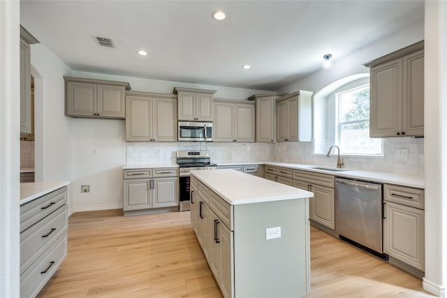 kitchen featuring light hardwood / wood-style flooring, a center island, appliances with stainless steel finishes, and tasteful backsplash