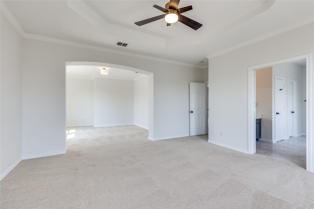 spare room featuring a tray ceiling, ornamental molding, light carpet, and ceiling fan