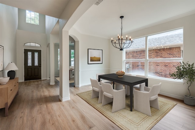 dining room with ornamental molding, light hardwood / wood-style flooring, and a notable chandelier