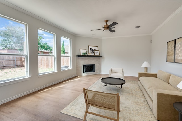 living room featuring crown molding, a wealth of natural light, ceiling fan, and light hardwood / wood-style floors