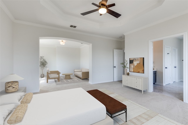 bedroom featuring a tray ceiling, crown molding, light colored carpet, and ceiling fan