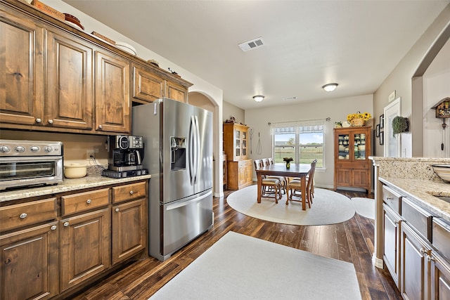 kitchen with stainless steel fridge with ice dispenser, light stone counters, and dark hardwood / wood-style floors