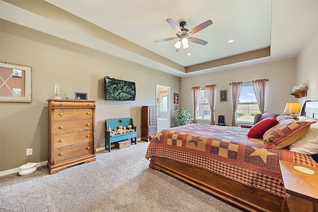 bedroom with a tray ceiling, ceiling fan, and carpet