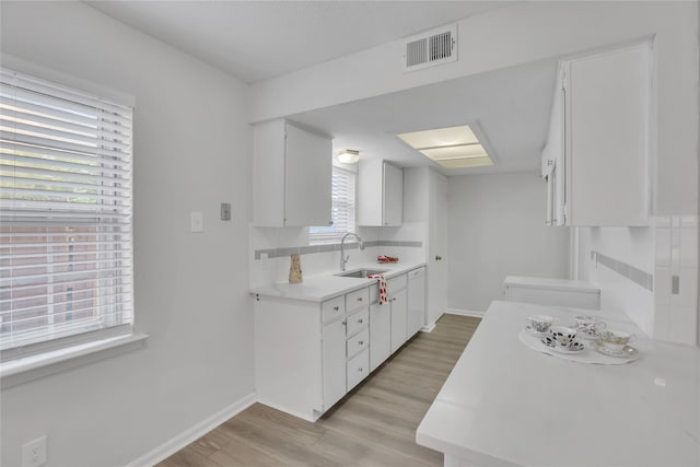 kitchen with light hardwood / wood-style floors, tasteful backsplash, sink, and white cabinets