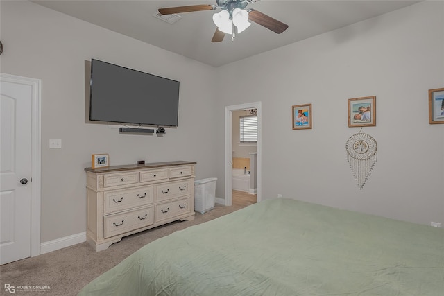 bedroom with ensuite bathroom, light colored carpet, a ceiling fan, baseboards, and visible vents