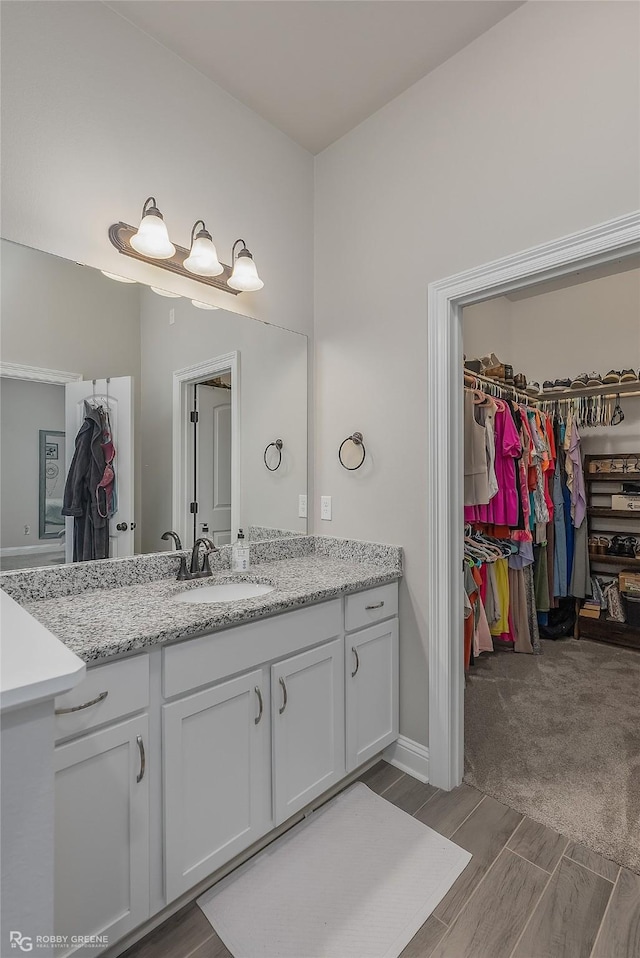 bathroom with wood finish floors, vanity, and a spacious closet