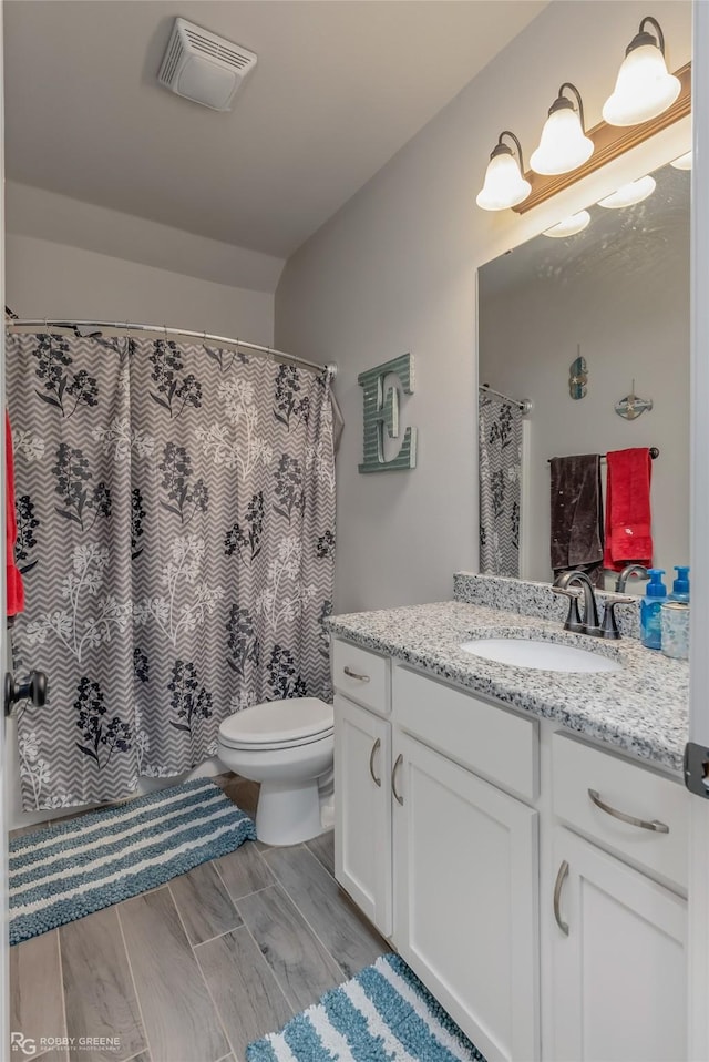 full bathroom with visible vents, toilet, curtained shower, wood tiled floor, and vanity