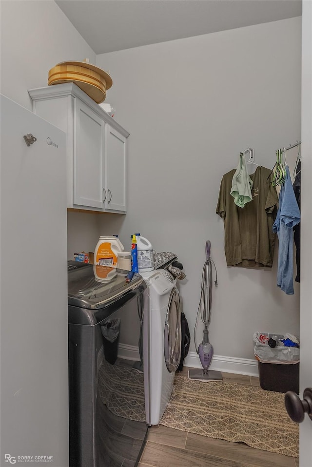 laundry area with wood finish floors, cabinet space, washer and clothes dryer, and baseboards