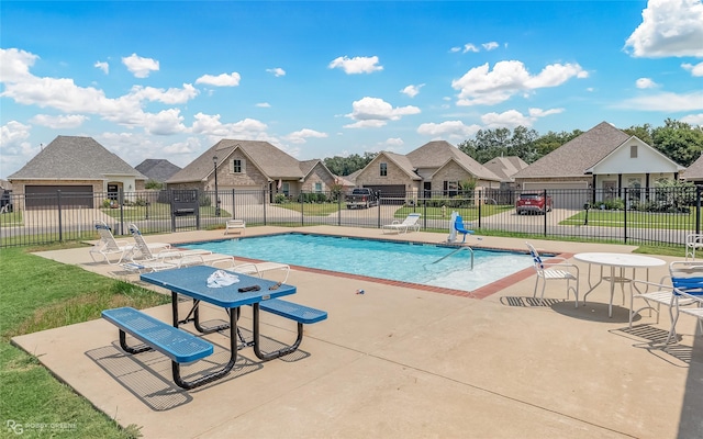 pool with a residential view, a patio area, fence, and a lawn