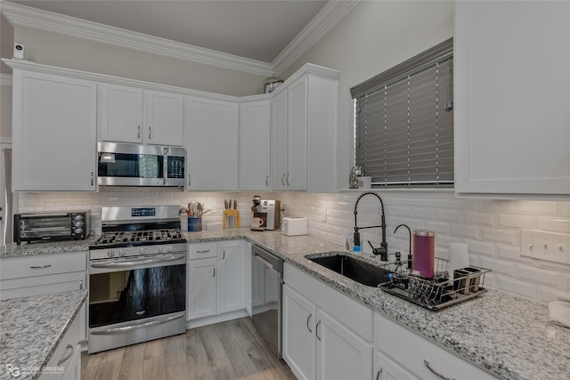 kitchen with a toaster, stainless steel appliances, white cabinets, ornamental molding, and tasteful backsplash