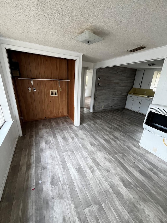 interior space with a textured ceiling, heating unit, and light hardwood / wood-style floors