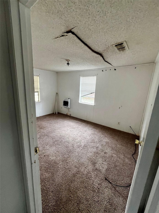 carpeted empty room featuring a textured ceiling and heating unit