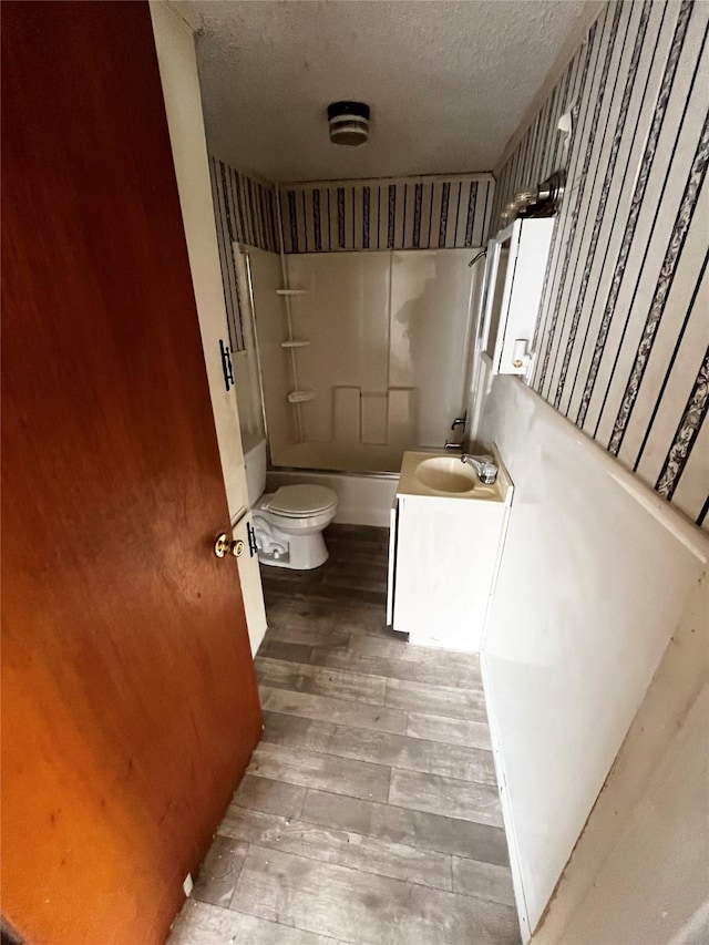 full bathroom with a textured ceiling, shower / bathing tub combination, vanity, toilet, and hardwood / wood-style flooring