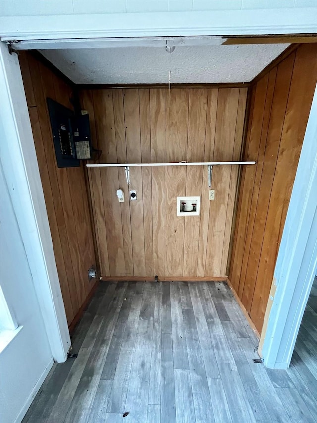 washroom featuring a textured ceiling, dark hardwood / wood-style flooring, hookup for a washing machine, and wooden walls