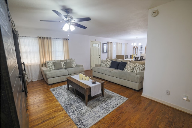 living room with dark wood-type flooring and ceiling fan with notable chandelier