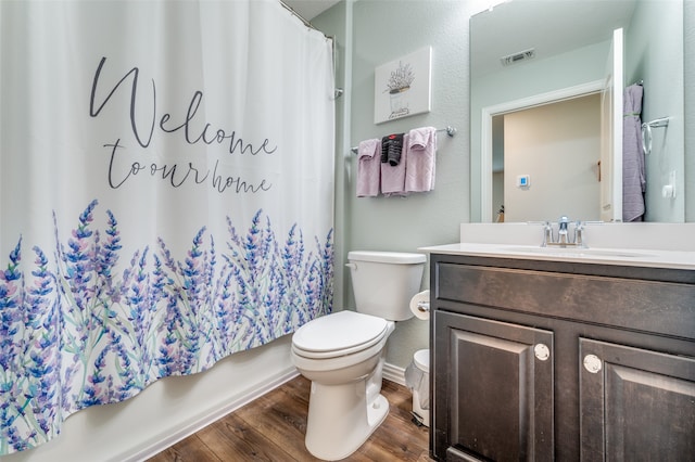 full bathroom featuring wood-type flooring, vanity, shower / tub combo, and toilet