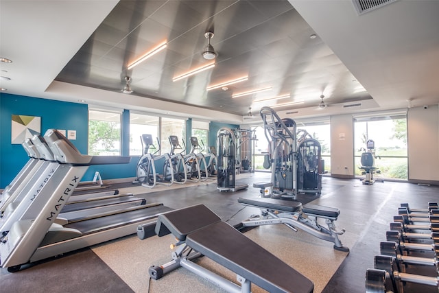 workout area with a raised ceiling and ceiling fan