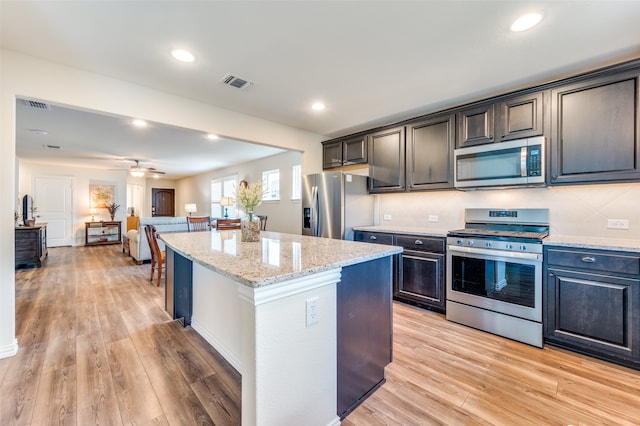 kitchen featuring ceiling fan, light hardwood / wood-style flooring, a kitchen island, and appliances with stainless steel finishes