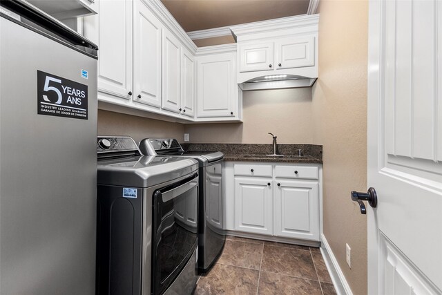 clothes washing area featuring crown molding, separate washer and dryer, cabinets, and sink