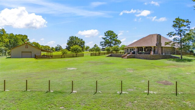 view of yard with a garage, a rural view, and an outdoor structure