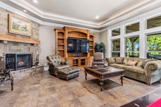 living room featuring a fireplace, a raised ceiling, and ornamental molding