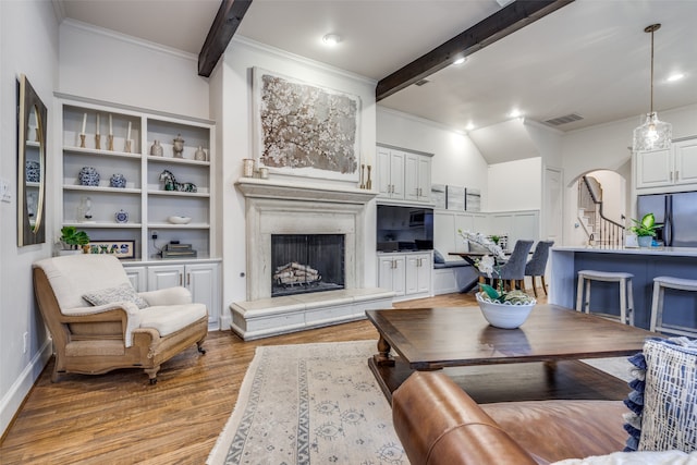 living room with ornamental molding, beamed ceiling, and light hardwood / wood-style flooring