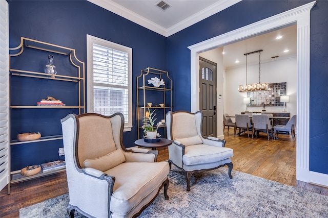 sitting room featuring wood-type flooring, crown molding, and a chandelier