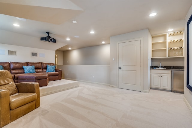 cinema room featuring wet bar and light colored carpet