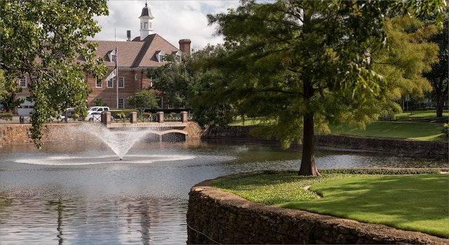 view of property's community with a lawn and a water view