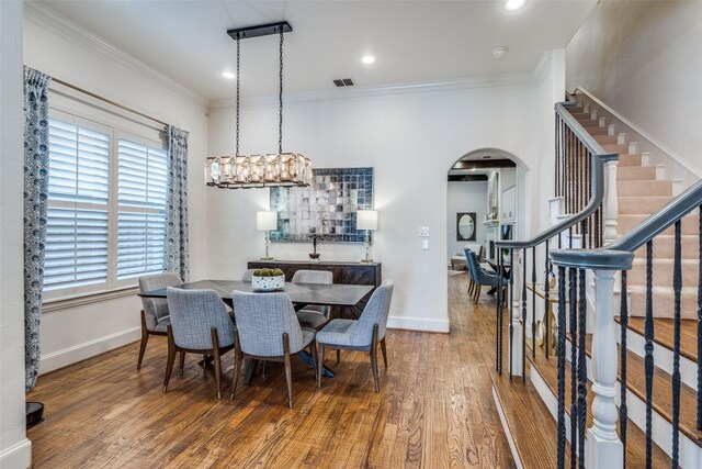 dining room with ornamental molding, a notable chandelier, and hardwood / wood-style flooring