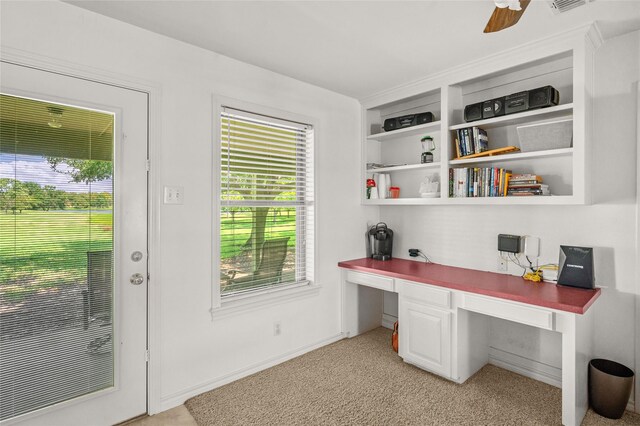 carpeted home office with ceiling fan and built in desk