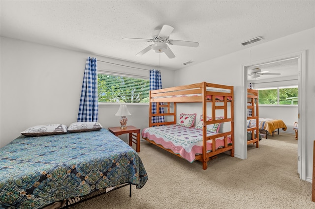 bedroom with ceiling fan, carpet, and a textured ceiling